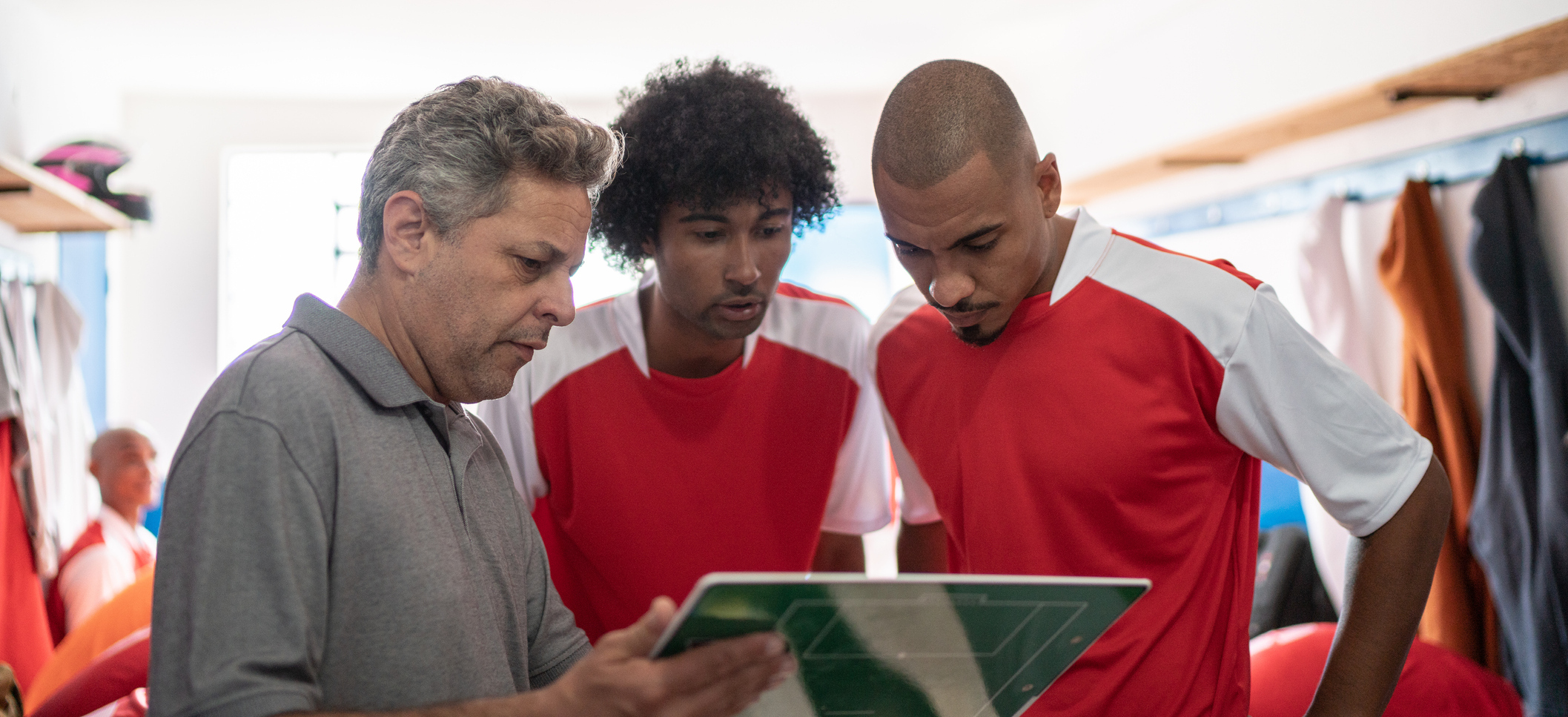 Gathered around a play board in the local room, a coach shares game strategy based on sports analytics insights revealed through annotation and analysis of the previous night’s game.