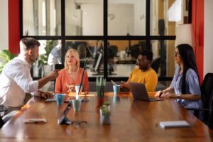 Equipo diverso de profesionales que colaboran en soluciones financieras digitales, simbolizando la intersección entre el código, el capital y el cambio en la transformación de los servicios financieros.