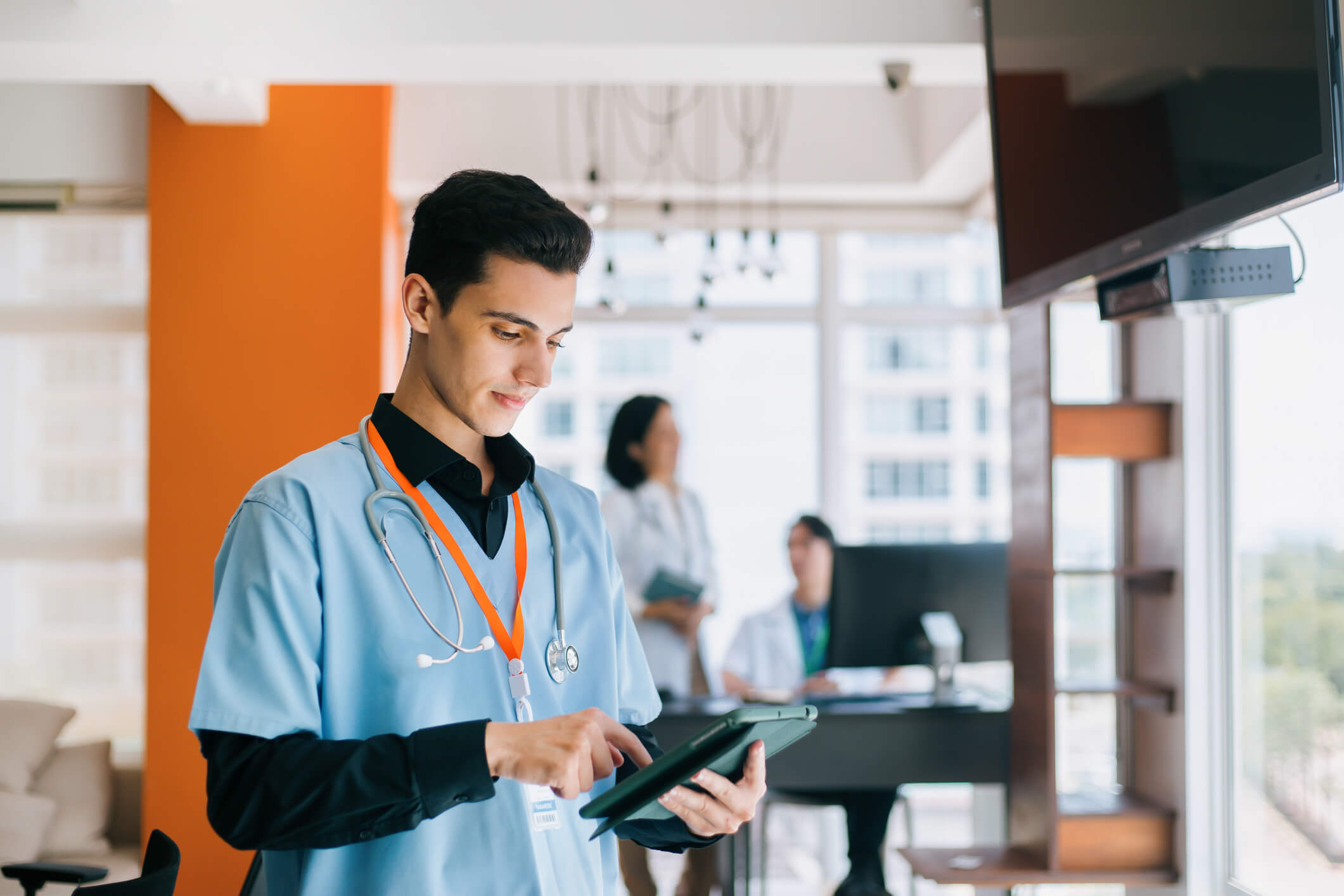 Male nurse using a digital tablet to engage with AI-enabled healthcare systems, reflecting the shift in healthcare trends toward intelligent, connected care delivery.