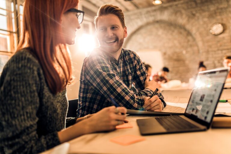 Two digital engineers in a brightly lit office discuss their collaboration on an AI-driven solution designed to engineer business impact.