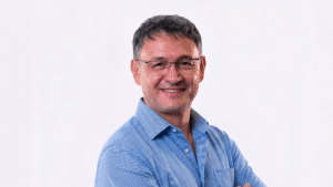 MarioRotim - GlobalLogic Portrait of a smiling man in a blue dress shirt with glasses (head-and-shoulders).”,