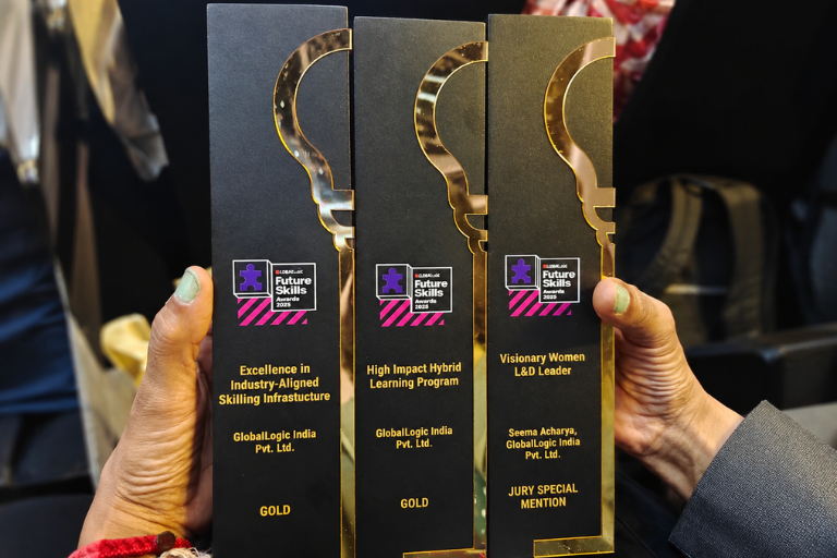Three black Future Skills Awards trophies with gold outlines, held by two hands.
