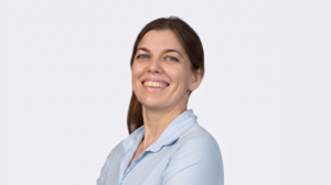 Alla_Danchenko_1130x635_V1-1024x575 - GlobalLogic Smiling woman in a light blue blouse looking at the camera, portrait against a pale background.